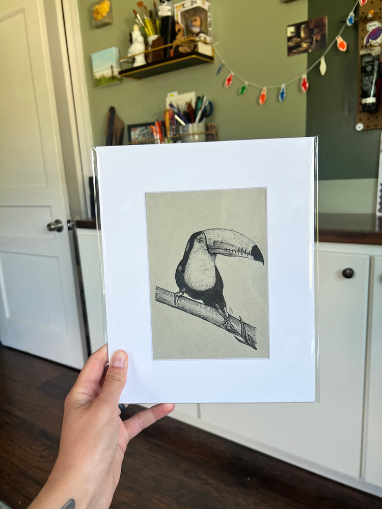 A hand holding a framed bird drawing.
