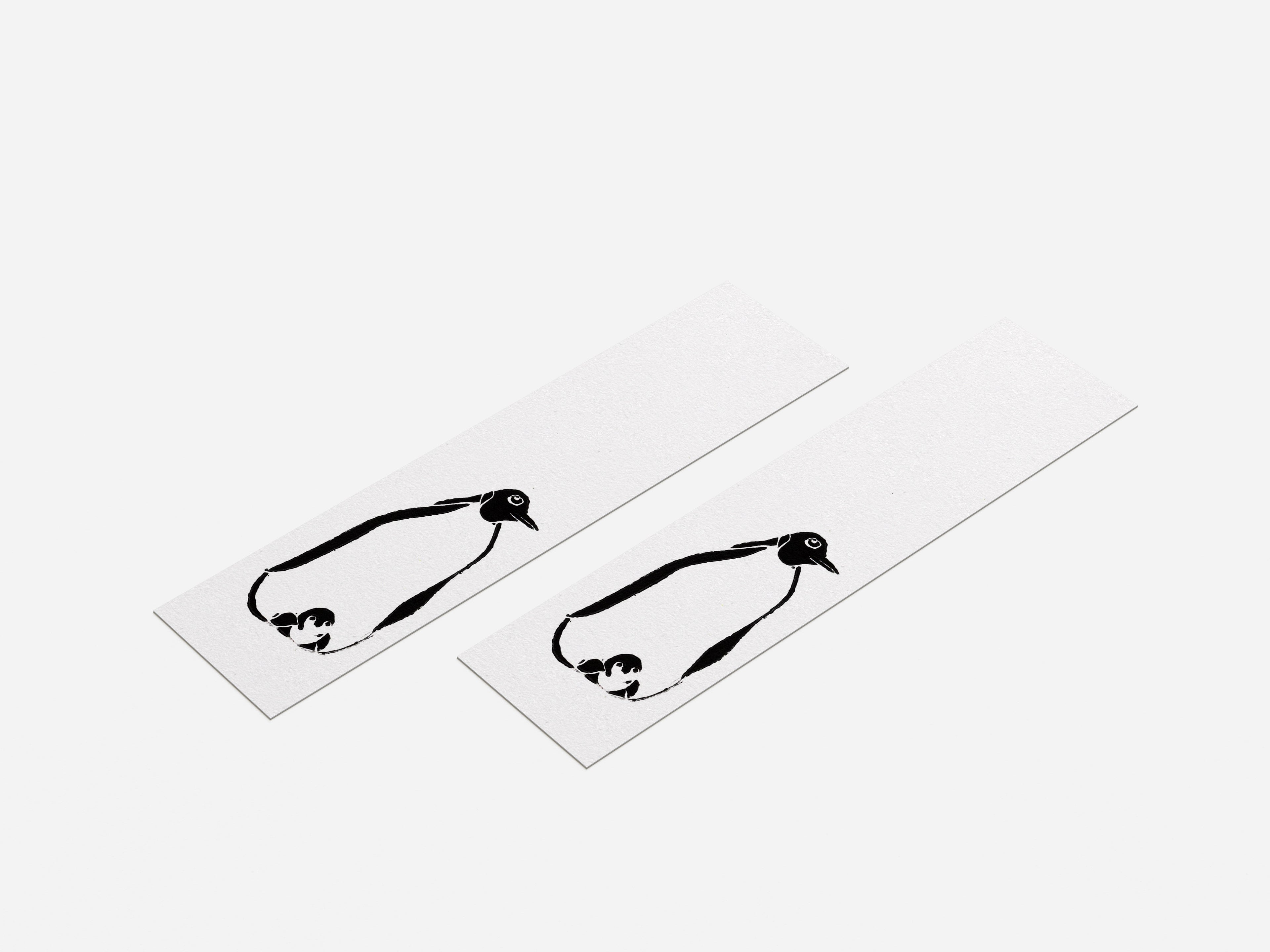 Two black and white penguin bookmarks on white paper