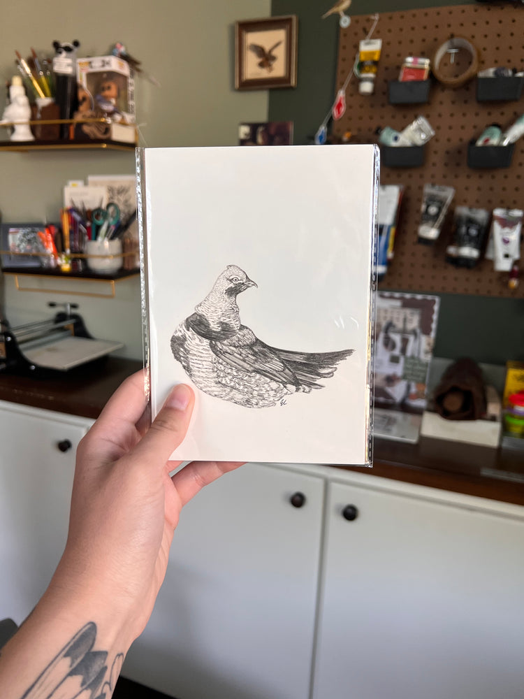 Matted illustration of a bird held by a person in a workshop setting