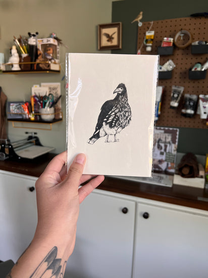 Matted illustration of a bird held by a person in a workshop setting