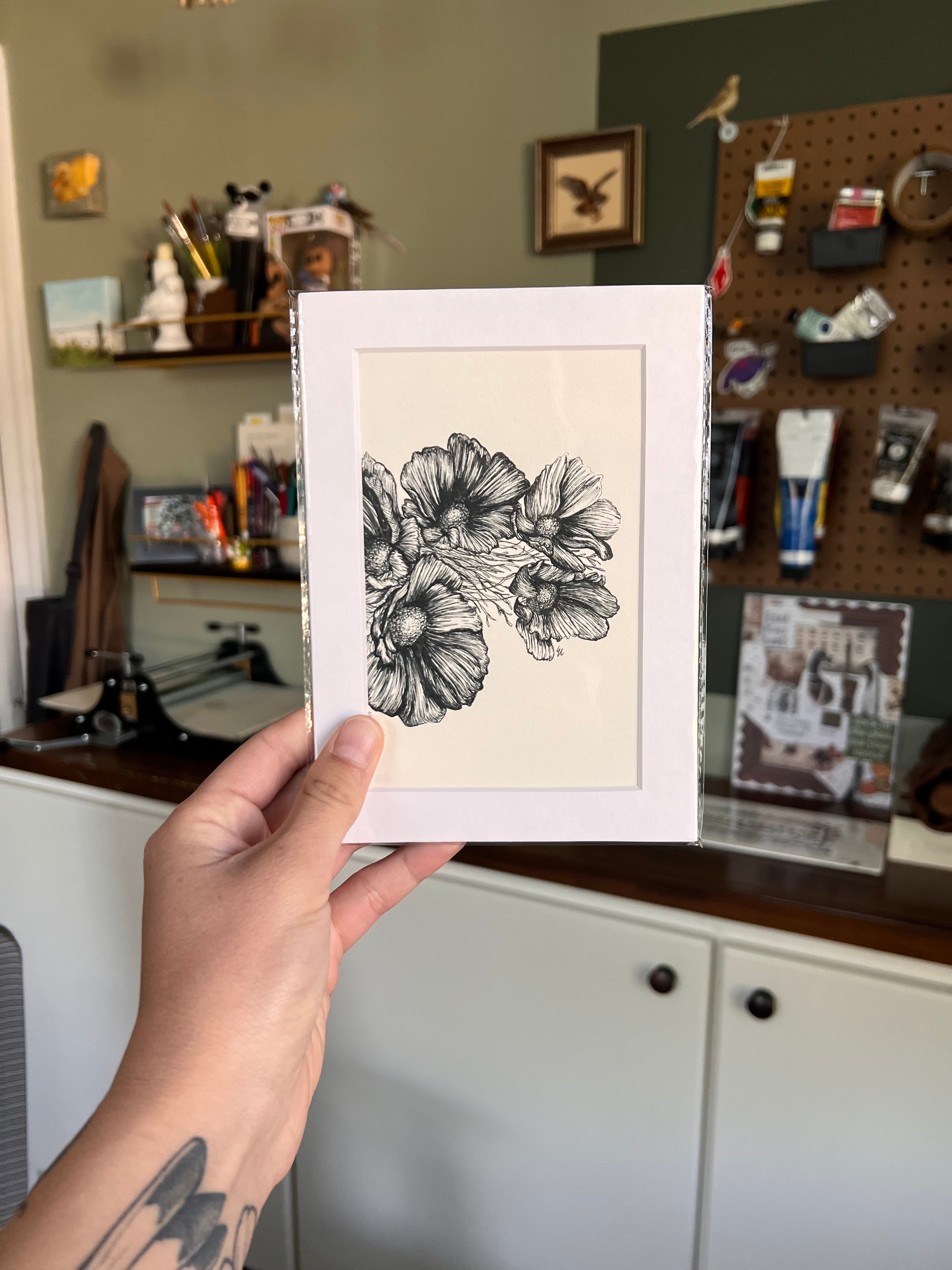 Matted illustration of a bird held by a person in a workshop setting