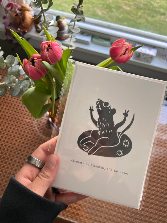 Hand holding a card with a black mouse riding an inner tube design.