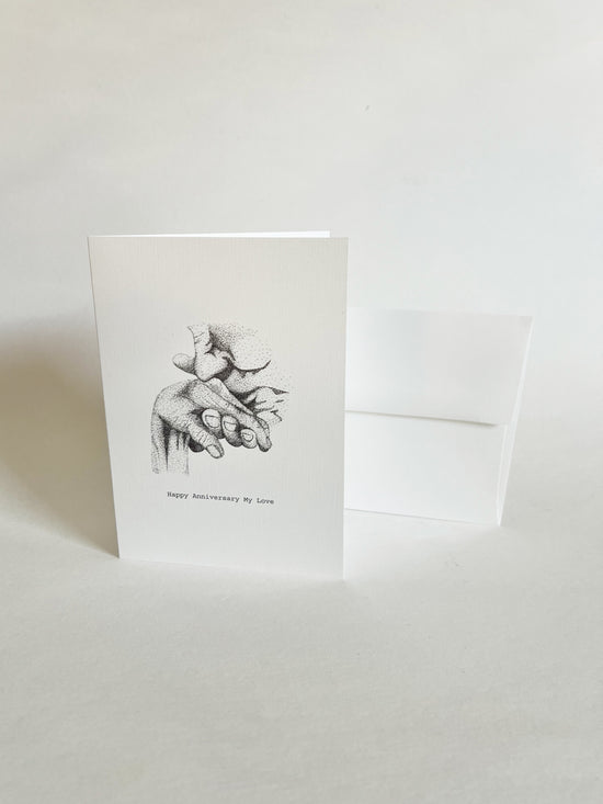 Greeting card with black and white illustration of a hand holding where a man is kissing a women's hand on a white background