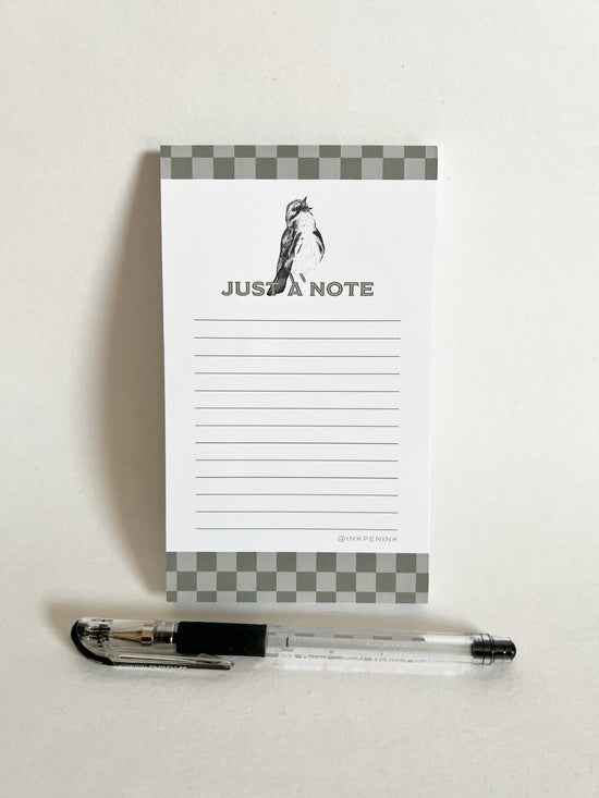 Notepad with 'Just a Note' text and a pen on a white background