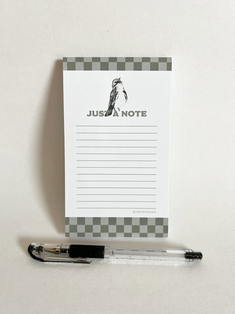 Notepad with 'Just a Note' text and a pen on a white background