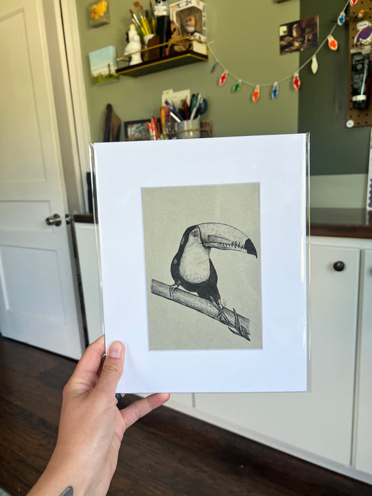 A hand holding a framed bird drawing.