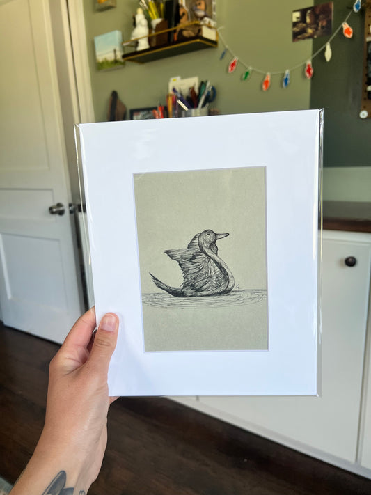 A hand holding a framed bird drawing.