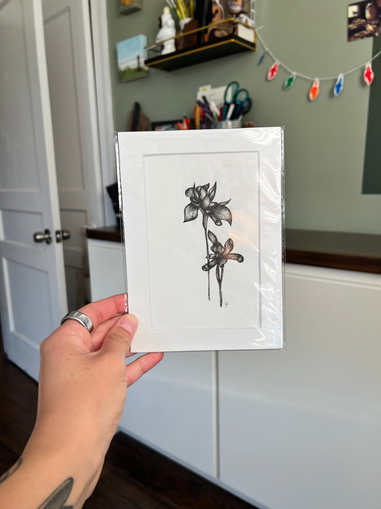 A hand holding a framed bird drawing.