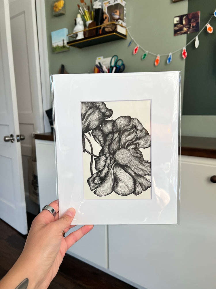 A hand holding a framed bird drawing.