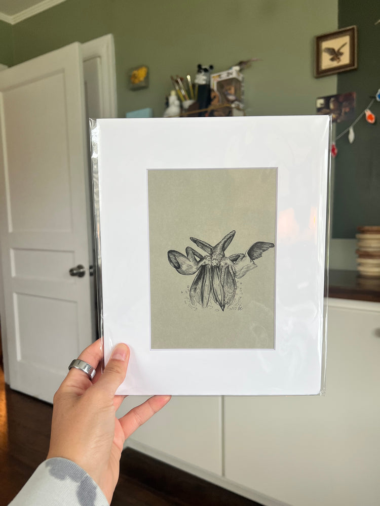 A hand holding a matted bird drawing.
