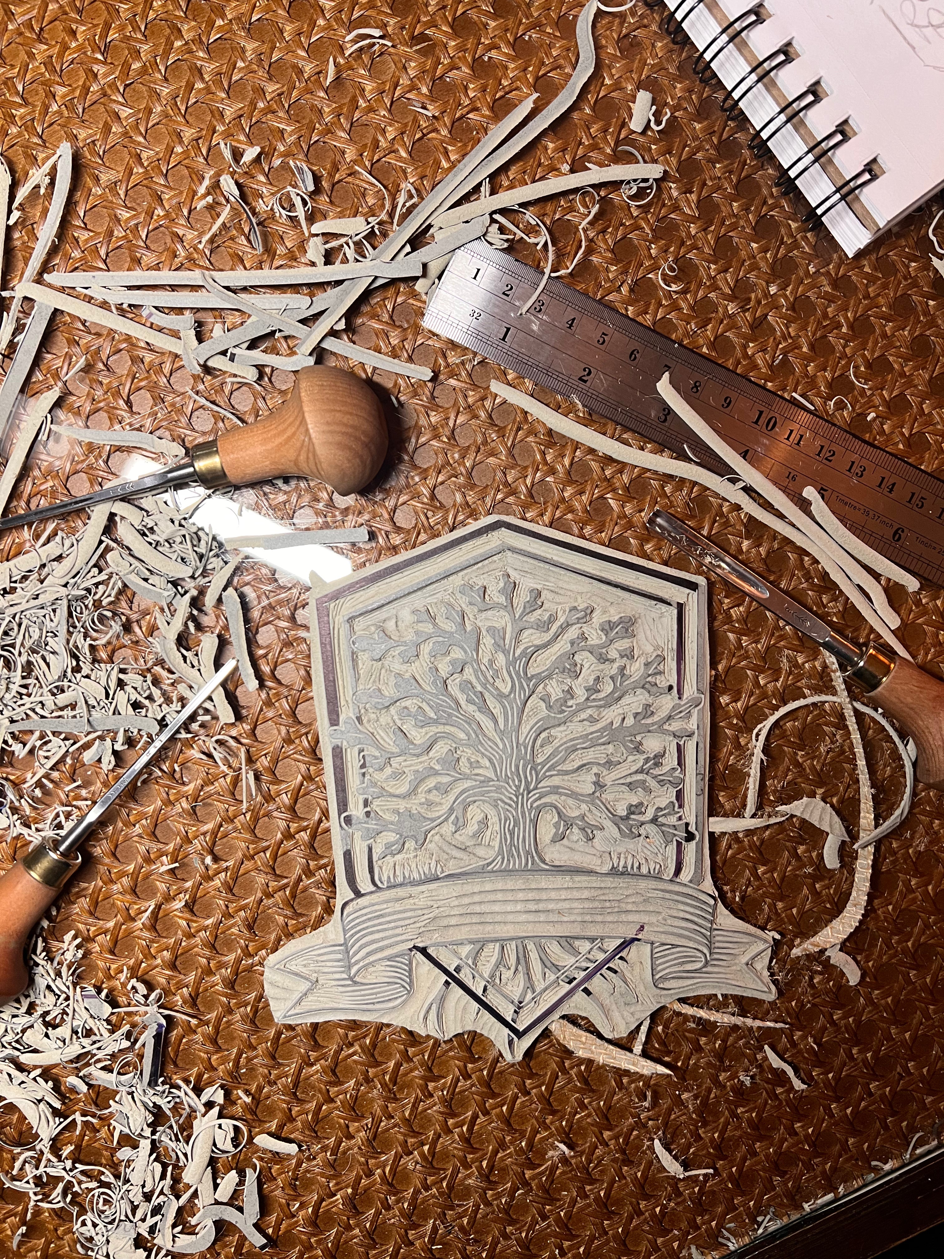 Wooden carving tool, carved linoleum design, and shavings on a brown surface